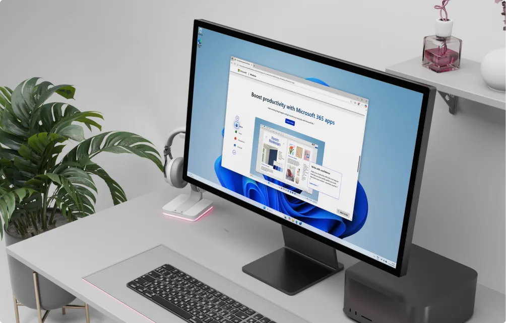 A modern desk setup with a large monitor displaying a Microsoft 365 productivity web page, a wireless keyboard, mouse, headphones, potted plant, and small decor items on a white desk.
