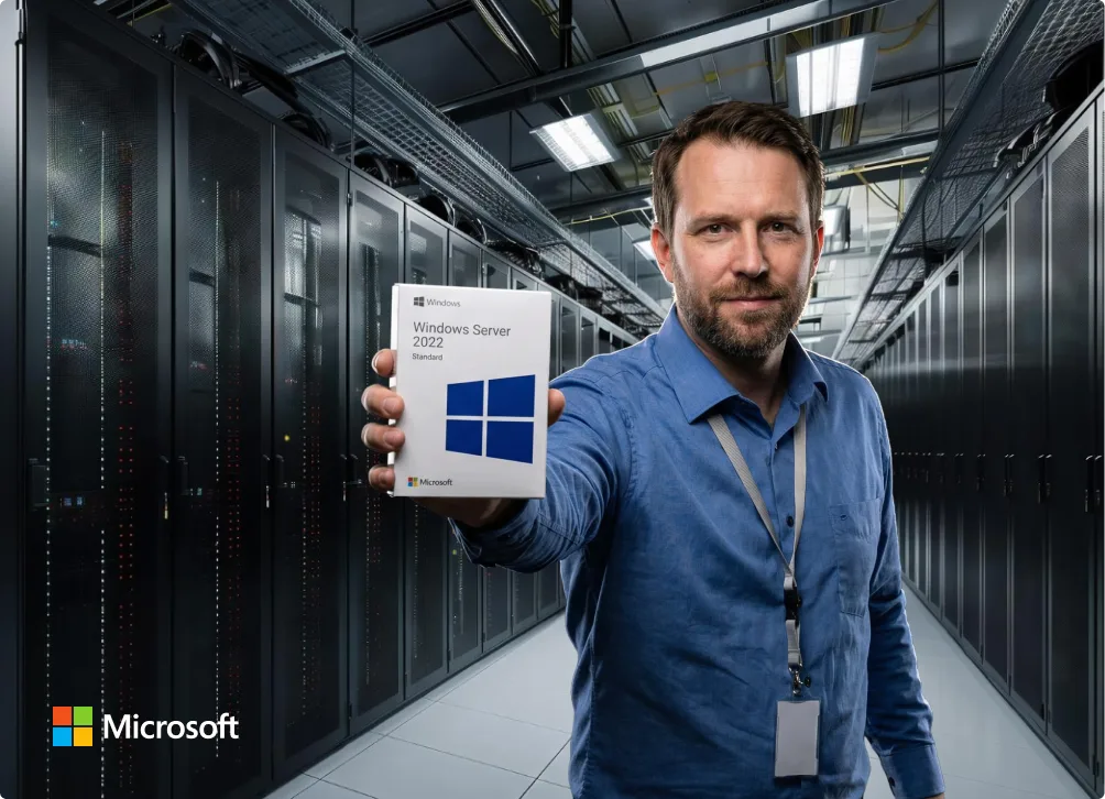 A man in a blue shirt stands in a server room, holding up a Windows Server 2022 Standard software box. Rows of server racks are visible behind him. The Microsoft logo is in the bottom left corner.